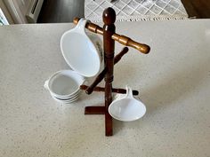 there is a wooden stand with three bowls on it and two spoons in the middle