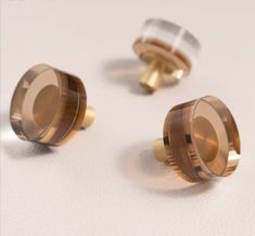 three gold colored knobs on a white surface