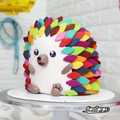 a cake decorated to look like a hedgehog with multicolored icing on it