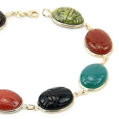 14k yellow gold gemstone scarab bracelet featuring 12 X 16 mm unikite, red jasper, black onyx, blue lace agate, blue onyx, carnelian, green onyx and tiger eye. Egyptian style scarab gemstones are hand set into 14K gold bezels and are connected to each other with 14K gold links. Details Length: 7 - 8.5 Inches Stone Size: Oval 16 X 12 mm Metal Type: 14K Gold Type Of Lock: Lobster Lock Fine Jewelry Bracelet With Cabochon, Luxury Oval Bracelet With Natural Stones, Luxury Oval Bracelets With Natural Stones, Oval Cabochon Bracelet In Fine Jewelry Style, Oval Cabochon Bracelets Fine Jewelry, Fine Jewelry Cabochon Bracelets As Gift, Oval Cabochon Bracelet Fine Jewelry, Adjustable Oval Cabochon Bracelet, Elegant Bracelets With Natural Stones