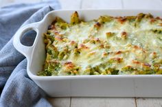 a casserole dish with broccoli and cheese in it on a wooden table