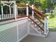 a wooden deck with white railing and wood handrails