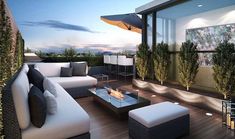 an outdoor living area with couches, tables and umbrellas on the roof terrace