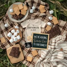 a table topped with marshmallows and cookies on top of a plaid blanket