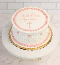 a white cake with pink frosting and gold trimmings on a marble table