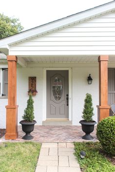 two large black planters sitting in front of a white house with wood trimming