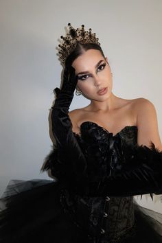 a woman wearing a black dress and tiara with feathers on her head is posing for the camera