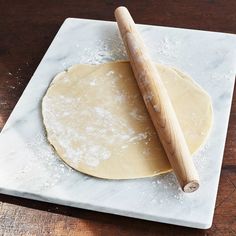 a wooden rolling pin sitting on top of a white marble counter next to a doughnut