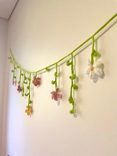 crocheted flowers are hanging from a string on the wall next to a bed