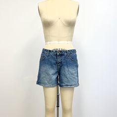 "Vintage  denim shorts featuring; traditional 5 pocket styling mid rise waist zip fly with single button at the waist Mudd leather patch on back at the waist Mudd  fabric tabs on coin pocket in front and back pocket thigh fade of a heavy weight cotton denim in a medium blue wash labeled \"For the Best Generation Mudd Jeans\" and tagged a size 11, measurements when laid out flat are; 16 inches at the waist 20 1/2 inches at the hip 10 inch rise 4 1/2 inch inseam in good, preworn, vintage condition Denim Cutoff Shorts With Hip Pockets, Cutoff Denim Shorts With Hip Pockets, Mid-rise Denim Blue Jean Shorts With Belt Loops, Medium Wash Jean Shorts With Five Pockets, Medium Wash Five-pocket Jean Shorts, Denim Shorts With Five Pockets, Mid-rise Denim Shorts With Belt Loops, Fitted Denim Shorts With Belt Loops, Trendy Jean Shorts With Hip Pockets