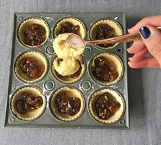 a person holding a spoon in a muffin tin