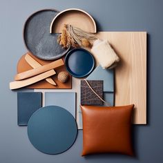 an assortment of different colors and materials on a blue surface with a leather cushion, pillow, bowl, plate, spoons and other items