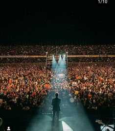 a man standing on top of a stage in front of a large group of people