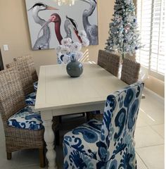 a dining room table with blue chairs and a painting on the wall