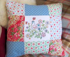 a patchwork pillow with flowers and birds on it