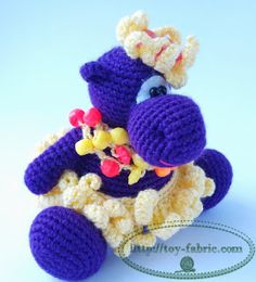 a crocheted purple and yellow stuffed animal sitting on top of a white table