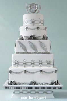 a three tiered wedding cake with feathers on the top, and an emblem above it