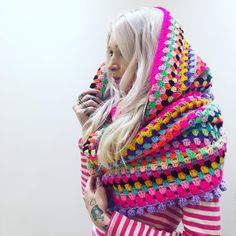 a woman with long blonde hair wearing a multicolored crocheted shawl