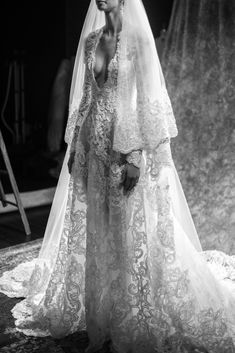 a woman in a wedding dress standing on a rug with a veil over her head