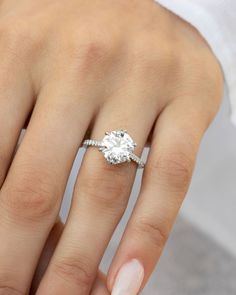 a woman's hand with a diamond ring on her finger and white nail polish