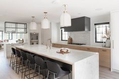 a large kitchen with an island and bar stools in the center, surrounded by windows