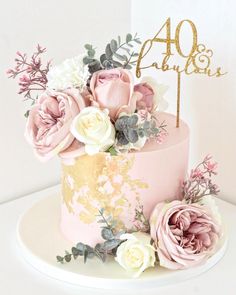 a pink and gold cake with flowers on top