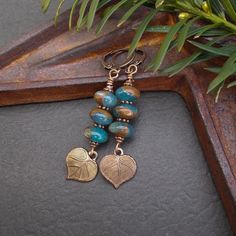 "Earthy and rustic earrings in a warm color palette. The stones are blue gold quartz, kind of a denim blue with large sections of warm brown. Below hang small but detailed bronze finished leaf charms. I've included antiqued copper plated beads and round copper plated  lever back wires. Earring Length: about 2 1/8\" including the wire Stone Size: about 10mm Leaf: about 1/2\" across Your earrings will arrive in an eco-friendly Kraft paper gift box. More Stone Earrings https://www.etsy.com/shop/BonArtsStudio?section_id=26432800 Nature Collection https://www.etsy.com/shop/BonArtsStudio?ref=ss_profile%2B%2B%2B%2B%2B%2B%2B%2B%2B%2B%2B%2B%3Fref&section_id=30222355 More Beaded Beauties: https://www.etsy.com/shop/BonArtsStudio?ref=seller-platform-mcnav&section_id=17052813 See What's New: https://ww Rustic Nickel-free Blue Jewelry, Blue Rustic Dangle Jewelry, Stack Earrings, Jewelry Rustic, Rustic Earrings, Copper Leaf, Beautiful Accessories, Unique Jewelry Gifts, Stacked Earrings