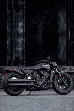 a black motorcycle parked in front of a building with dark paint on it's walls