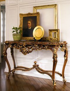 an ornate console table with a portrait on it