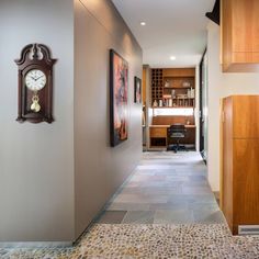 a clock mounted to the side of a wall next to a hallway with wooden cabinets