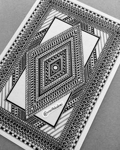 a black and white drawing on paper with an intricate design in the middle, sitting on top of a table