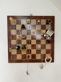 a chess board with jewelry hanging from it's sides and a cell phone on the wall