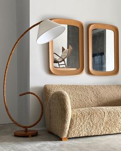 a living room with a couch and two mirrors on the wall above it, along with a lamp