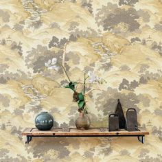 a vase with flowers on a shelf in front of a wallpapered background,