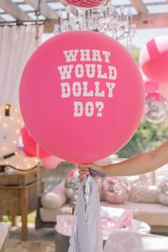 a woman holding a pink balloon with what would dolly do? written on it