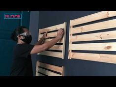 a woman wearing a face mask is placing wood pieces on the side of a wall