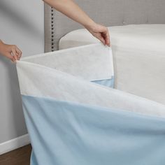 a person is unwrapping a bed with blue and white sheets