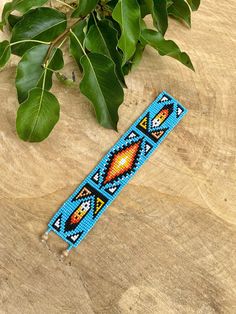 a blue beaded bracelet sitting on top of a wooden table next to a plant