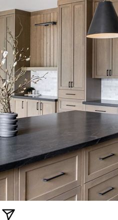 a large kitchen with wooden cabinets and black counter tops on the island in front of it