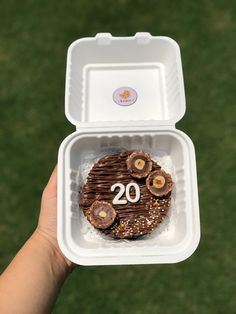 a person holding up a container with some food in it and the number 20 on it