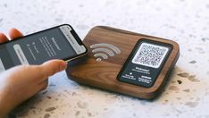 a person holding a cell phone next to a wooden device with qr code on it