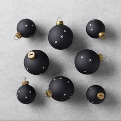 twelve black and gold christmas ornaments on a gray surface with space for the letter e