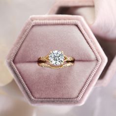 an engagement ring in a pink velvet box with a diamond center on the top and bottom