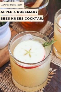 two glasses filled with apple cider sitting on top of a wooden table