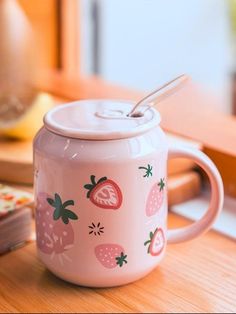 a pink coffee mug with strawberries on it