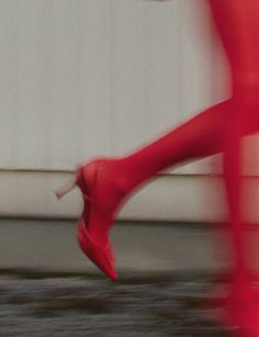 a woman in red high heels walking down the street