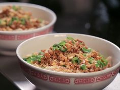 two bowls filled with rice and vegetables on top of a black countertop next to each other