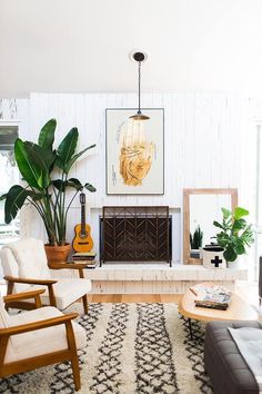 a living room filled with lots of furniture and plants on the wall above it's fireplace