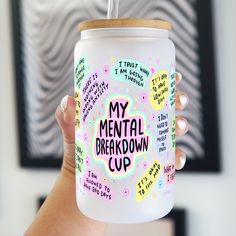 a person holding up a cup with writing on it