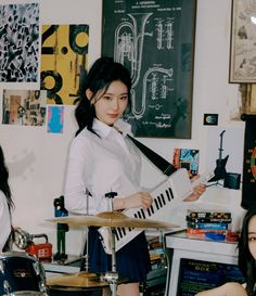 two young women are playing instruments in a room with posters on the wall behind them